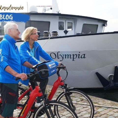 Couple de cyclotouristes devant le navire qui leur sert d'hébergement au cours de leur séjour en bateau & vélo