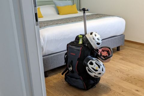 Valise étiquetée et casques à vélo dans une chambre d'hôtel