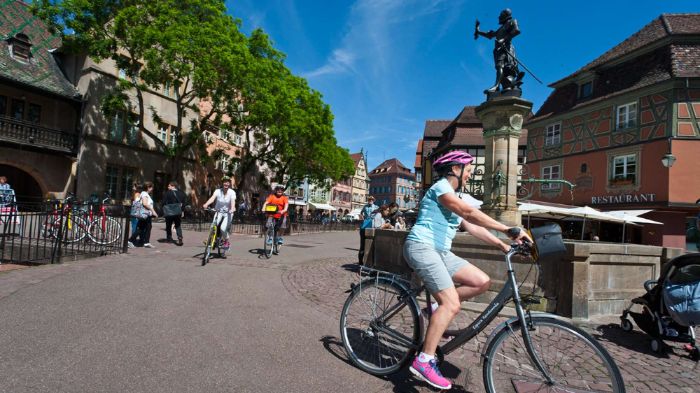 Cyclotouristes partis avec Espace Randonnée, roulent sur une place typique de la ville alsacienne de Colmar 
