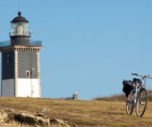 Vélo de randonnée garé devant le phare de Pen Men sur l'île de Groix en Bretagne