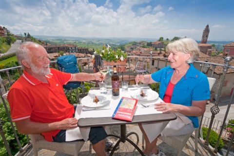 Couple attablé dans un restaurant en terrasse, avec une belle vue sur un village typique du Piémont